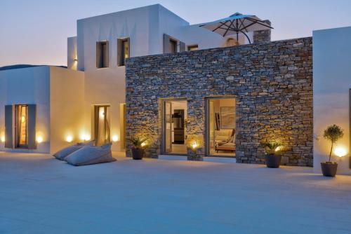 a villa with a large patio in front of a building at Golden Bay luxury villas and suites in Chrissi Akti