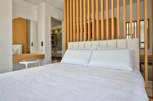 a bedroom with a large white bed with a wooden headboard at Golden Bay luxury villas and suites in Chrissi Akti