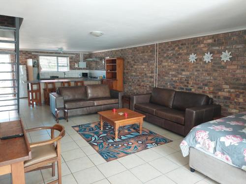 sala de estar con sofás de cuero y cocina en Clanwilliam Accommodation, en Clanwilliam