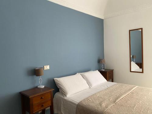 una camera da letto blu con un letto e uno specchio di Etna Rosso b&b a Catania