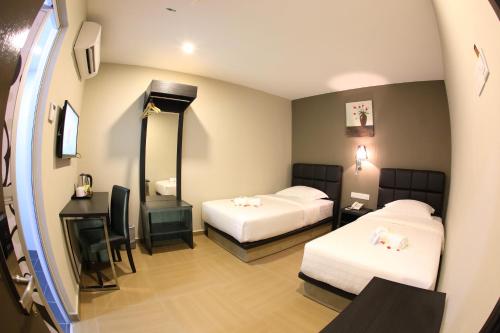a hotel room with two beds and a mirror at GL Hotel Kluang in Kluang