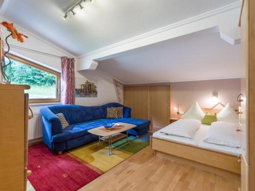 Una sala de estar con un sofá azul y una mesa. en Haus Agnes Daum, en Hippach