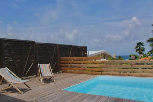 two chairs and a swimming pool on a wooden deck at Kaz Madinina Colibri in Le Diamant