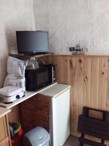 une cuisine avec un four micro-ondes et une télévision sur un comptoir dans l'établissement LA CABANE, à Bellac