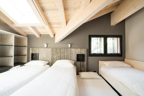 Tres camas en una habitación con techos de madera. en Le Petit Chalet de Montriond, en Montriond