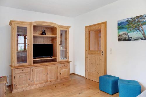 a living room with a tv in a wooden cabinet at Ferienwohnung Zugspitzblick in Grainau