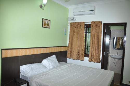 a bedroom with a bed and a sink at Jeyam Residency, Kumbakonam in Kumbakonam