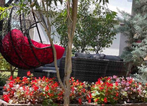 a red hammock sitting in a garden with flowers at Blue Garden Villa, Gjiri i Lalezit in Durrës