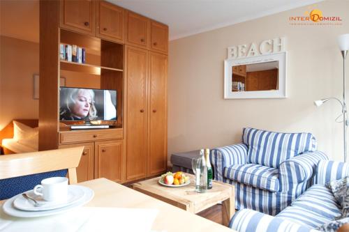 ein Wohnzimmer mit einem Sofa und einem TV in der Unterkunft Inselresidenz Strandburg Juist - Wohnung 106 (Ref. 50958) in Juist