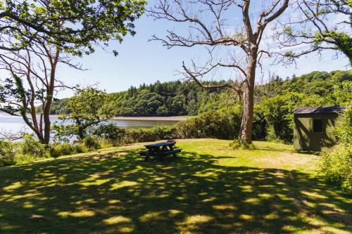 a picnic table sitting in the grass near a lake at Broomhill Barns in Minwear