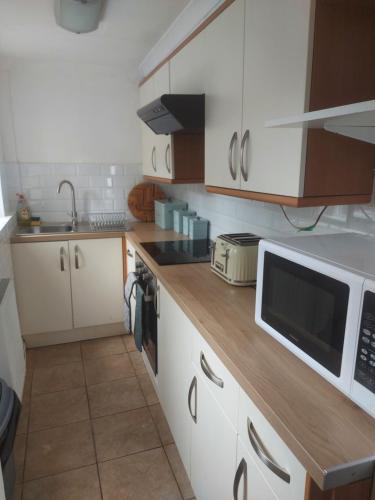 eine Küche mit weißen Schränken und einer weißen Mikrowelle in der Unterkunft York House in Conwy