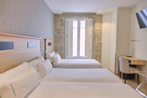 a hotel room with two beds and a television at Hotel Praza Quintana in Santiago de Compostela