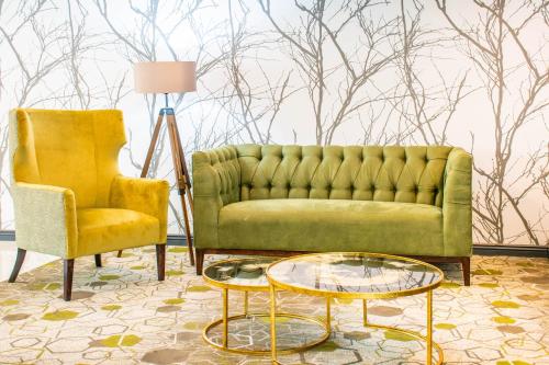 a living room with a green couch and a chair at Indaba Hotel, Spa & Conference Center in Johannesburg