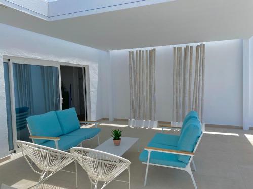 a living room with blue chairs and a table at Sea Sky Lanzarote in Playa Blanca