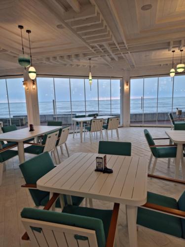a restaurant with tables and chairs and a view of the ocean at Dreamland Oasis Chakvi in Chakvi