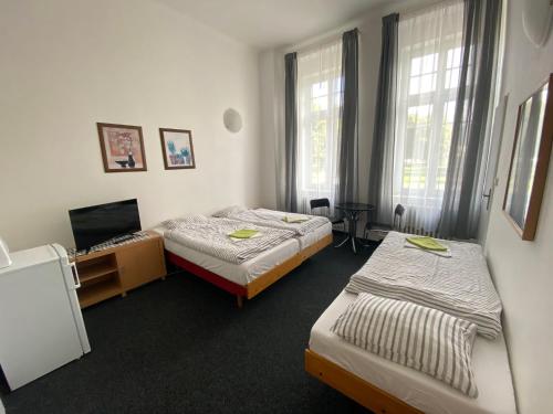 a hotel room with two beds and a television at Penzion Zahrada Čech in Litoměřice