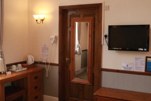 a room with a mirror and a television on the wall at Lion and Fiddle in Trowbridge