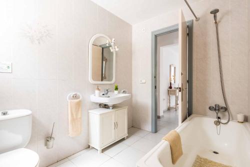 a white bathroom with a sink and a tub and a toilet at Villa Pepita in Binibeca