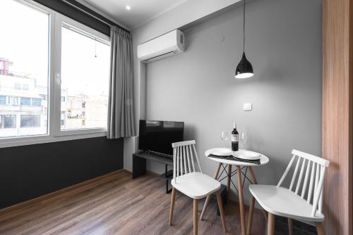 een woonkamer met een tafel en twee stoelen en een televisie bij WallStreet, The Luxury Suites in Thessaloniki