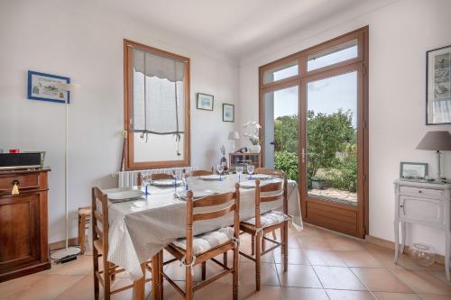 une salle à manger avec une table et des chaises et une fenêtre dans l'établissement Belle maison pour 6 au coeur des marais salants, à Guérande