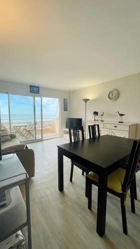 a living room with a black table and chairs at Appartement avec balcon vue mer in Merlimont
