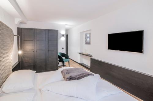 a bedroom with a bed and a tv on a wall at B&B Zur Traube in Vipiteno