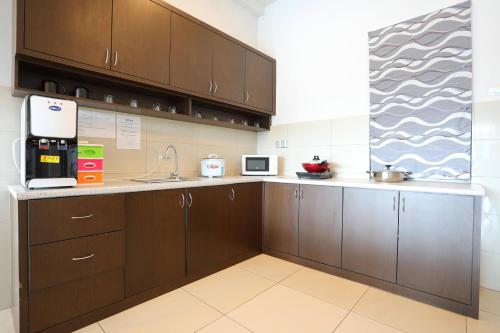 a kitchen with brown cabinets and a sink at AJ Suites @ Loft Imago KK in Kota Kinabalu