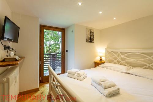una camera da letto con un grande letto bianco con asciugamani di TEMPORARYFLAT MONT CHETIF a Courmayeur