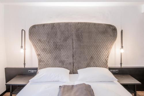 a bedroom with a large headboard and two tables at B&B Zur Traube in Vipiteno