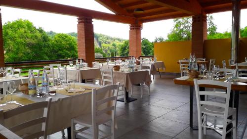 un ristorante con tavoli e sedie bianchi e alberi di Agriturismo Monsereno Horses a Imbersago