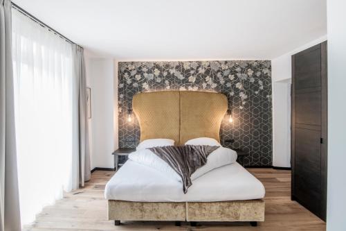 a bedroom with a large bed with a headboard at B&B Zur Traube in Vipiteno