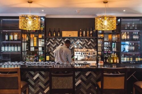 a man standing behind a bar in a restaurant at Indaba Hotel, Spa & Conference Center in Johannesburg
