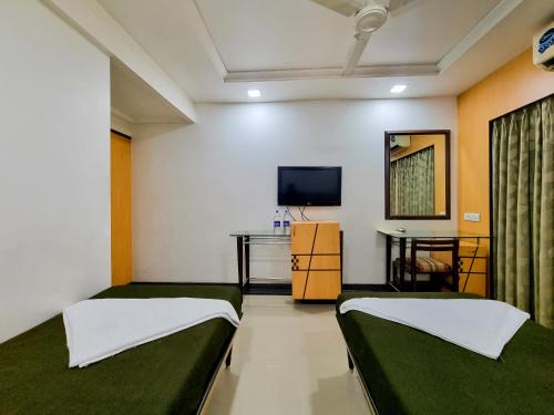 a room with two beds and a flat screen tv at Hotel Balwas International in Mumbai