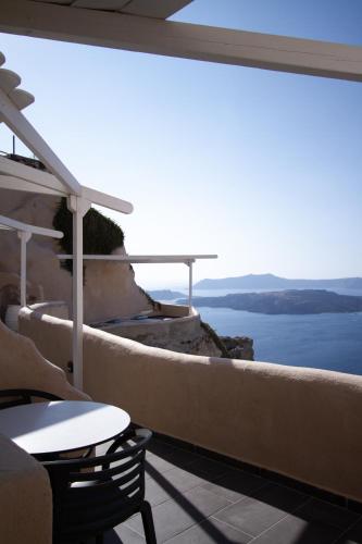 a balcony with a table and a view of the ocean at Suites of the Gods Cave Spa Hotel in Megalochori