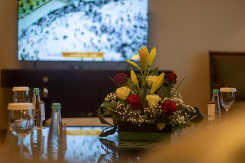 a vase of flowers on a table with a television at Abha Palace Hotel in Abha