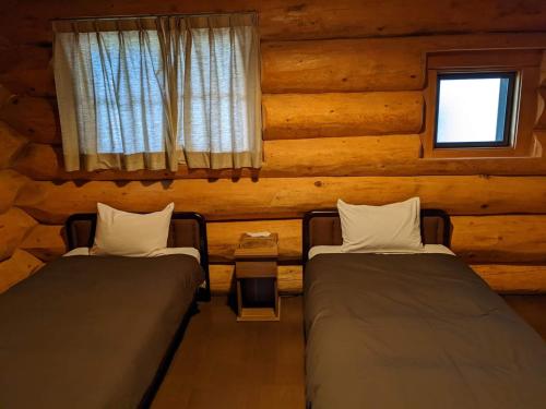 Habitación con 2 camas en una cabaña de madera en White Tree Log House Madarao Tangram, en Shinano