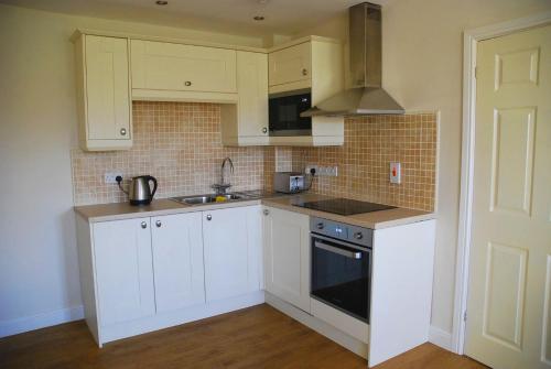 a kitchen with white cabinets and a sink and a stove at Lake House Annexe - beautiful countryside retreat in Bristol