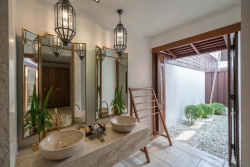 a bathroom with two sinks and two mirrors at Malisa Villa Suites - SHA Extra Plus in Kata Beach