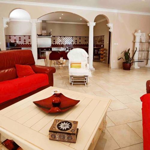un salon avec un canapé rouge et une table dans l'établissement Villa des Pins - Jolie villa proche de la plage, au Grau-dʼAgde