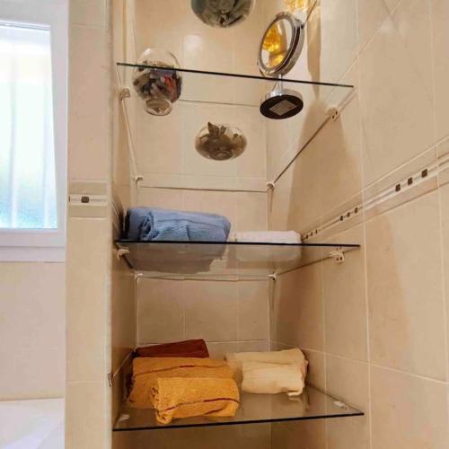 La salle de bains est pourvue de 3 étagères et de serviettes. dans l'établissement Villa des Pins - Jolie villa proche de la plage, au Grau-dʼAgde