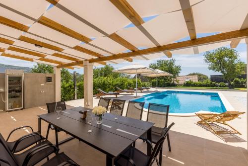a patio with tables and chairs and a swimming pool at Melki for 12 people with private pool in Klis