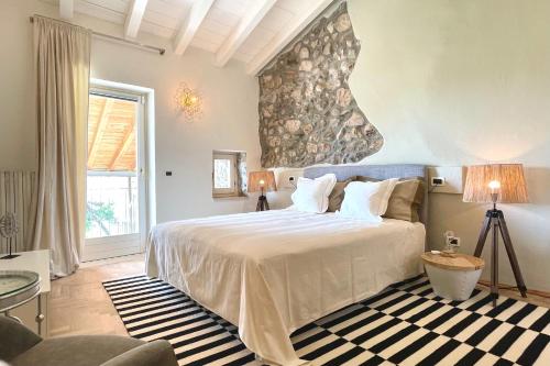 1 dormitorio con 1 cama grande y pared de piedra en Borgo dei Sogni - Unique Loft - Lago di Garda, en San Felice del Benaco