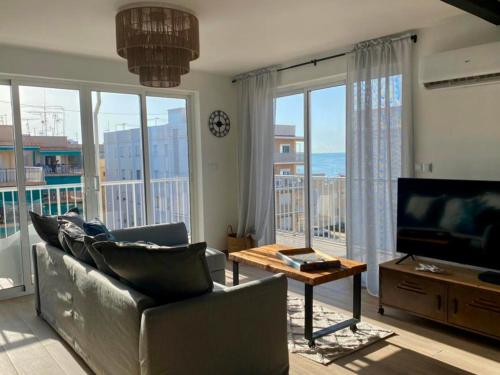 a living room with a couch and a tv and a table at SunPola Penthouse in Santa Pola