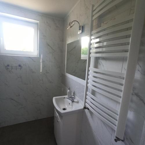 een witte badkamer met een wastafel en een spiegel bij W cieniu Szarloty in Rydułtowy