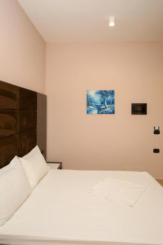 a bedroom with a white bed and a painting on the wall at Aliko Hotel in Vlorë