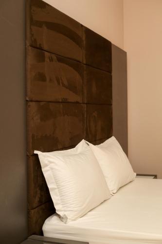 a bed with a brown headboard and two white pillows at Aliko Hotel in Vlorë