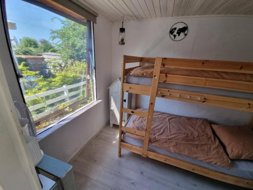 Lazy cabin near Hoek van Holland beach في هوك فان هولاند: سرير بطابقين في غرفة مع نافذة