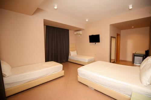 a hotel room with two beds and a flat screen tv at Aliko Hotel in Vlorë