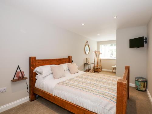 a bedroom with a wooden bed with a tv on the wall at Daisy Tree Cottage in Woodhall Spa