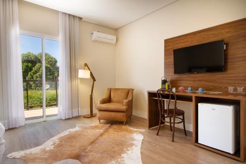 Cette chambre comprend un bureau avec une télévision et une chaise. dans l'établissement Hotel Chateau, à Campos do Jordão